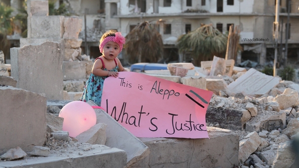 Growing up in Aleppo: Sama of the title holds a banner bearing a pathetic message