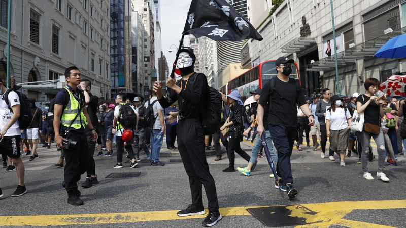 A protester wearing a Guy Fawkes mask holds a flag during a rally to abolish the anti-mask law in Hong Kong