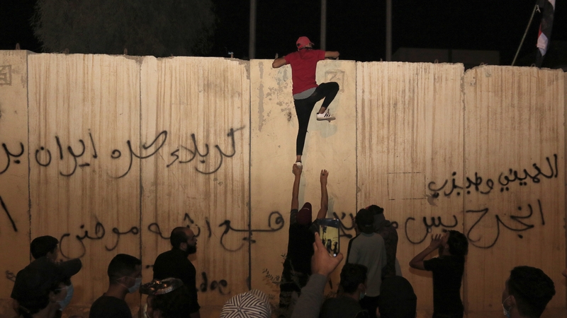 A protester attempts to climb the wall outside the Iranian consulate in Kerbala