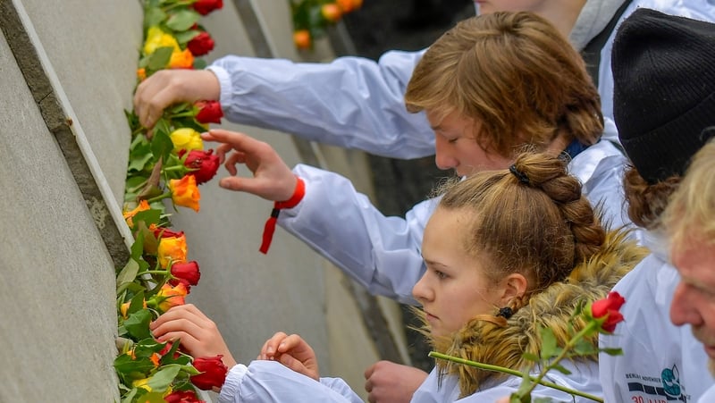 People place flowers at the Wall Memorial for the 30th anniversary of the fall of the Berlin Wall
