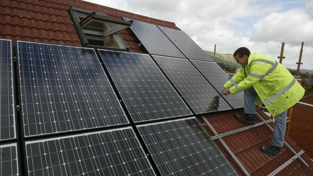 A man installs solar panels on a roof