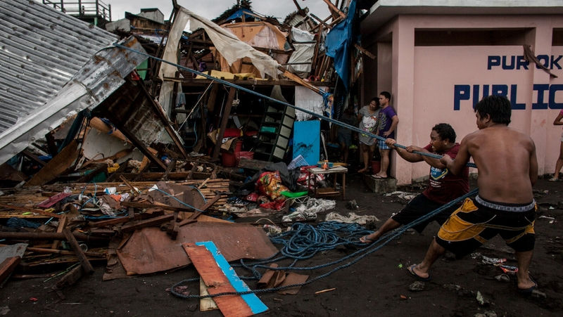 Villagers working among damaged houses in the aftermath of Typhoon Kammuri