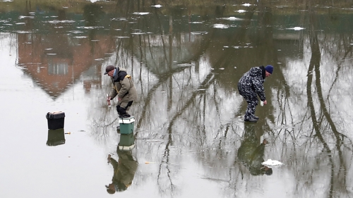 Russian men fish on a pond covered in thin ice in Moscow