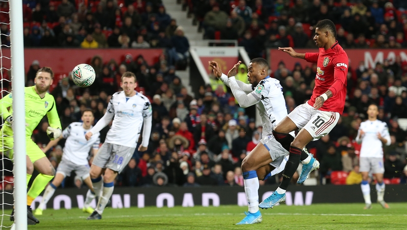 Ryan Jackson of Colchester United scores an own goal under pressure from Marcus Rashford