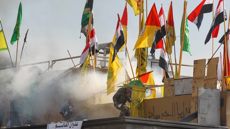 US forces (unseen) fire teargas canisters at supporters and members of the Hashed al-Shaabi paramilitary force