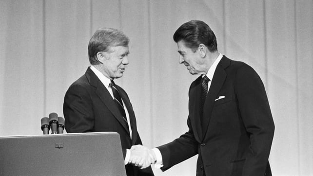 Jimmy Carter and Ronald Reagan shake hands before a debate