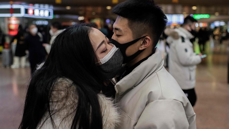 A couple wearing protective masks embrace at a Beijing railway station