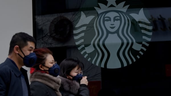 People wearing protective face masks walk past a closed Starbucks coffee shop in China