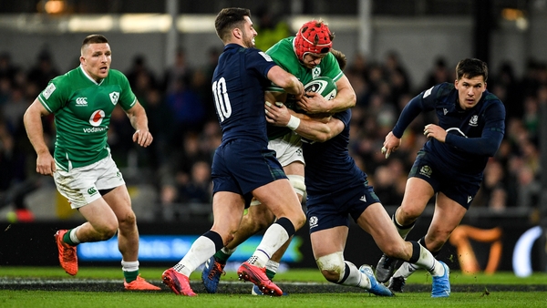 Josh van der Flier of Ireland is tackled by Adam Hastings (L) and Rory Sutherland of Scotland