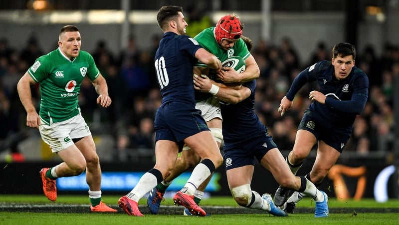 Josh van der Flier of Ireland is tackled by Adam Hastings (L) and Rory Sutherland of Scotland