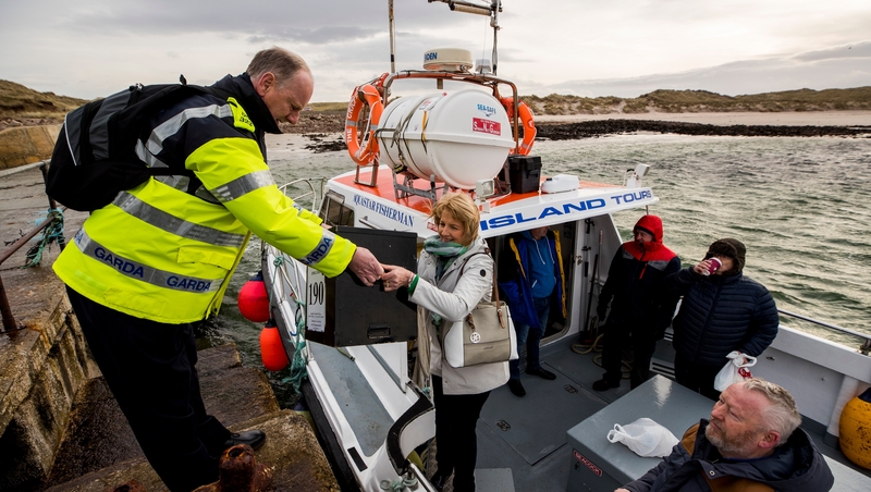 Presiding officer Nancy Sharkey hands over the ballot box to Garda Tom McBride as they arrive on Gola island