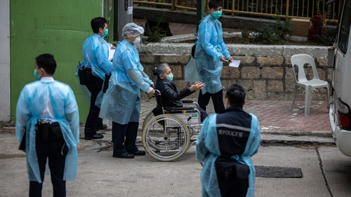 A woman is evacuated from a public housing scheme in Hong Kong after residents tested positive for the virus