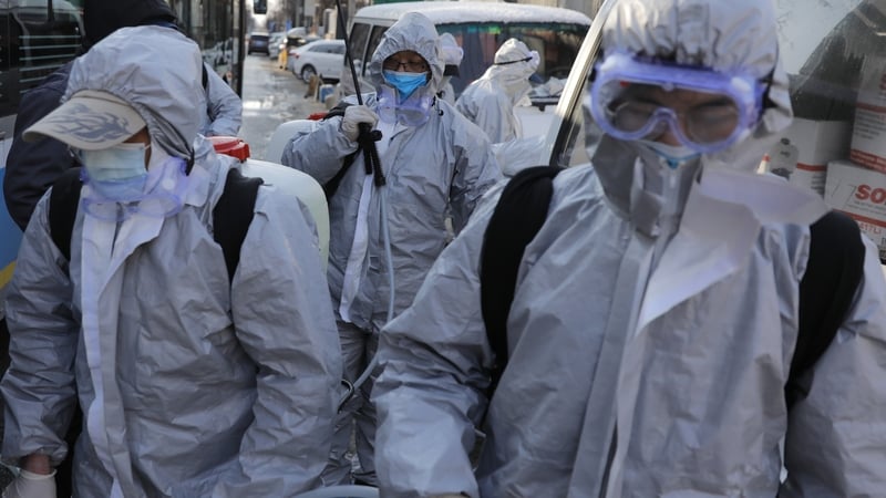 Workers wearing protective suits gather after they disinfected a residential area in Beijing