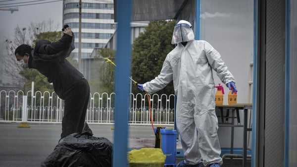 A worker disinfects a recovered COVID-19 patient departing a temporary hospital in Wuhan