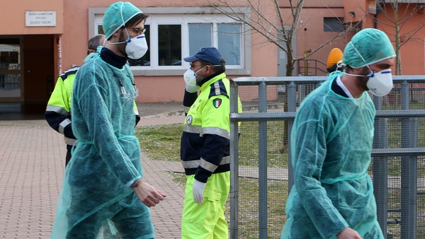 People wear protective face masks in front of a closed elementary school in Vo' Euganeo, Padua, Italy