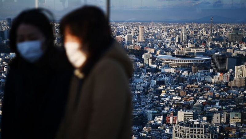 People wearing face masks with the New National Stadium, the main venue for the 2020 Tokyo Olympic Games, in the background