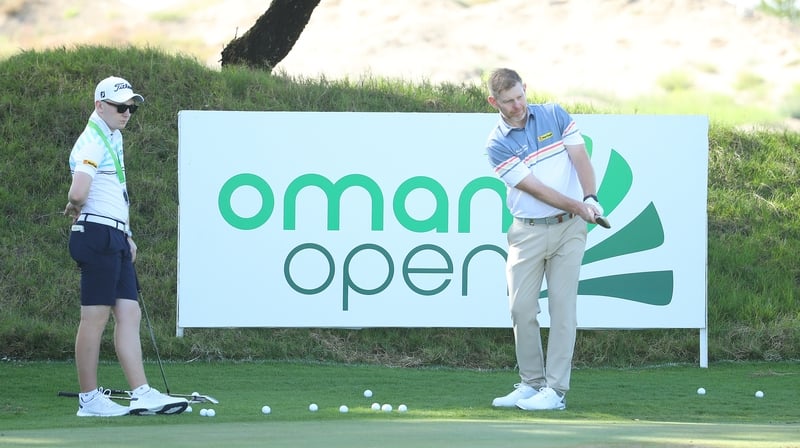 Stephen Gallacher of Scotland practices watched by his son and caddie Jack at the Oman Open