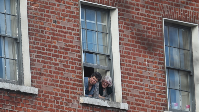 Search party: People look out of a window waiting for the arrival of the royals