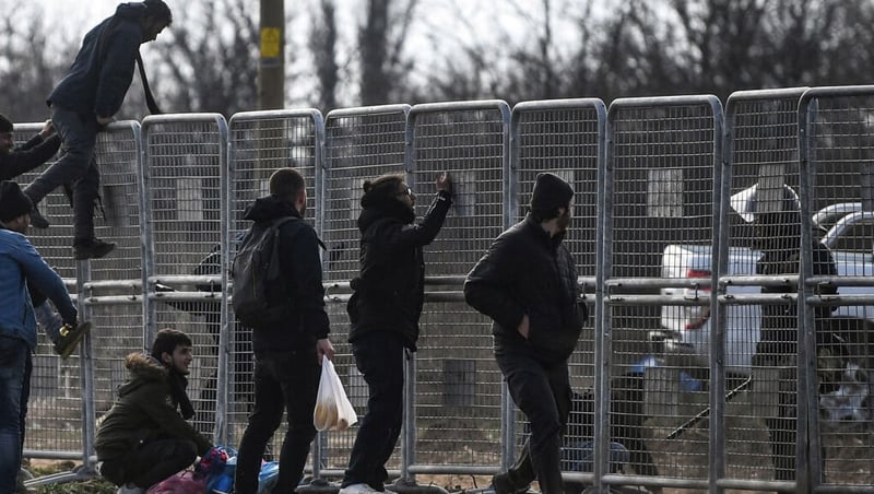 A soldier stands guard as migrants attempt to scale fences erected by the Turkish army