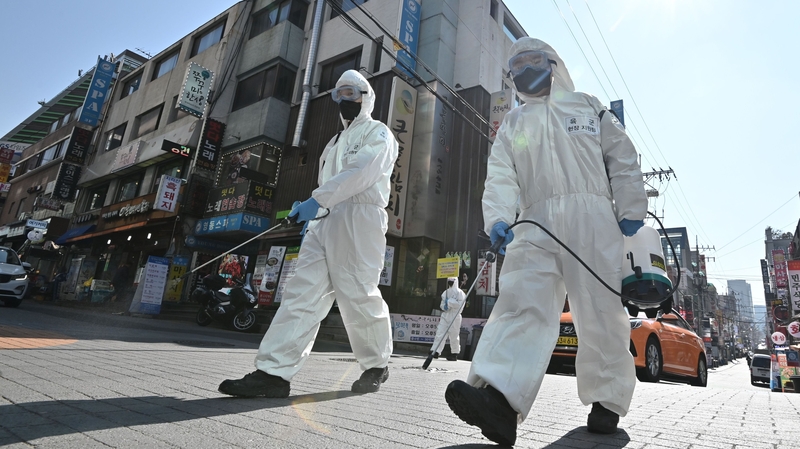 South Korean soldiers wearing protective gear spray disinfectant on a street in Seoul