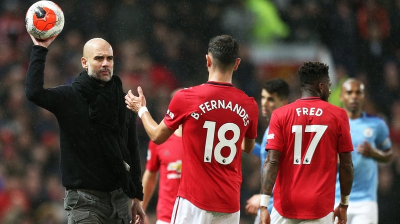 Pep Guardiola hands the ball to Bruno Fernandes during the Manchester derby