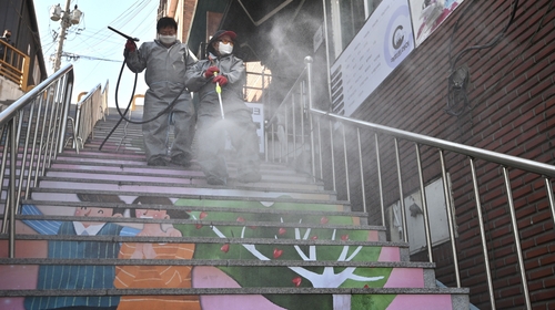 A worker wearing protective gear sprays disinfectant next to a building housing the Grace River Church, where 46 people were confirmed to have Covid-19