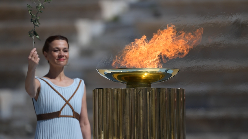 A perfomer stands next to the Olympic flame during the handover ceremony for the 2020 Tokyo Summer Olympics