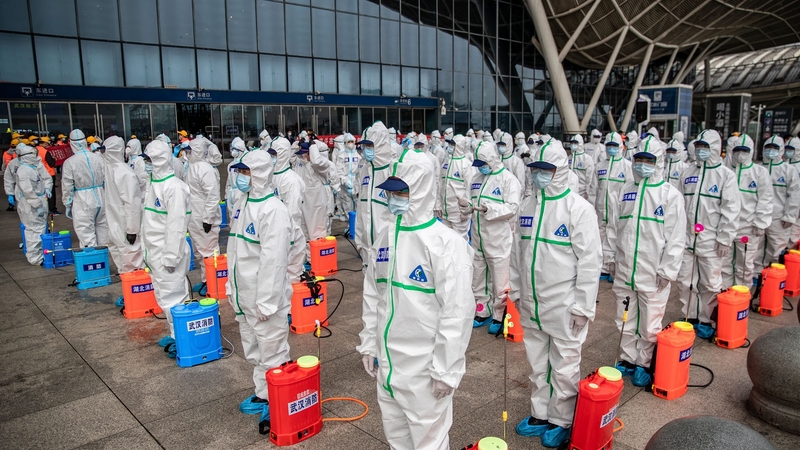 Staff members line up as they prepare to spray disinfectant at Wuhan Railway Station