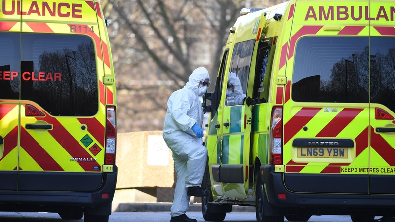 A member of the ambulance service leads a patient into an ambulance at St Thomas' Hospital in London