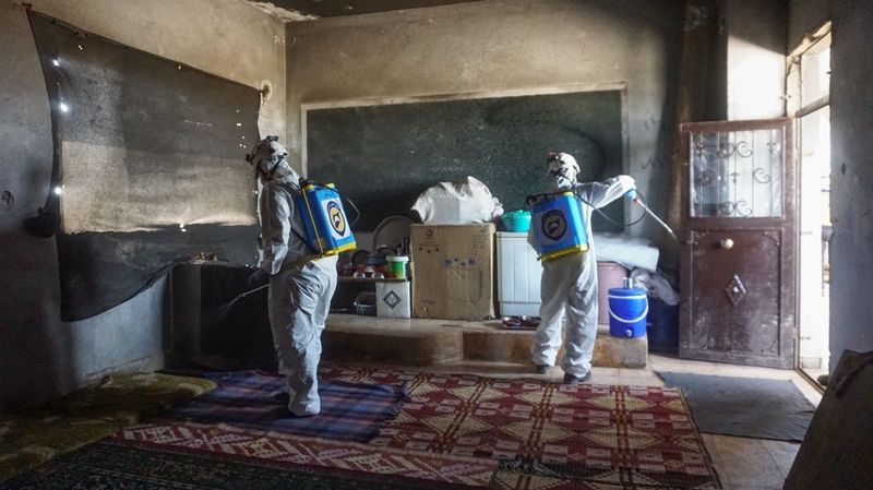 Members of the Syrian civil defence disinfect a former school building currently inhabited by displaced families in Binnish in Syria