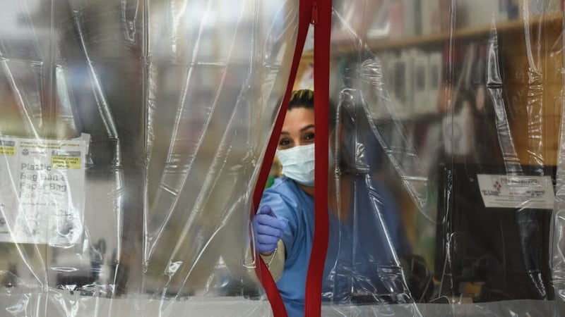 A pharmacist works behind plastic sheeting while wearing protective equipment in the Elmhurst area of New York City