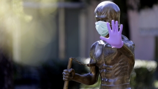 A statue dedicated to martial arts icon Bruce Lee, wearing surgical gloves and a face mask, in Bosnia