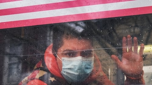 A man waves from a bus in a neighborhood in the Queens borough, which has one of the highest infection rates of coronavirus in the United States