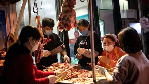 Workers wearing facemasks and gloves make a barbecue at a market in Wuhan last Saturday. Photo: Noel Celis/AFP via Getty Images