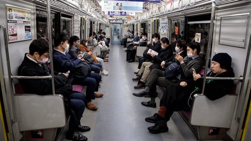 People wearing face masks amid concerns over the spread of Covid-19 commute on a train in Tokyo