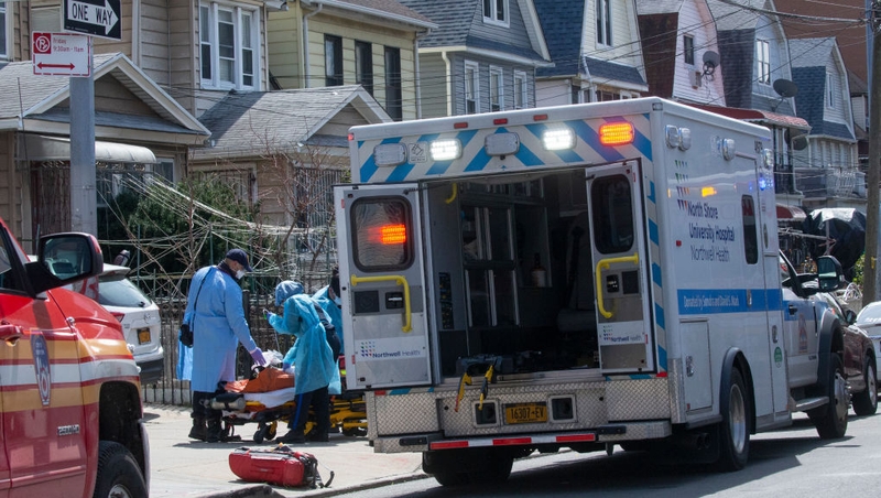 First responders carry a patient on a stretcher from a house in the Queens borough of New York City