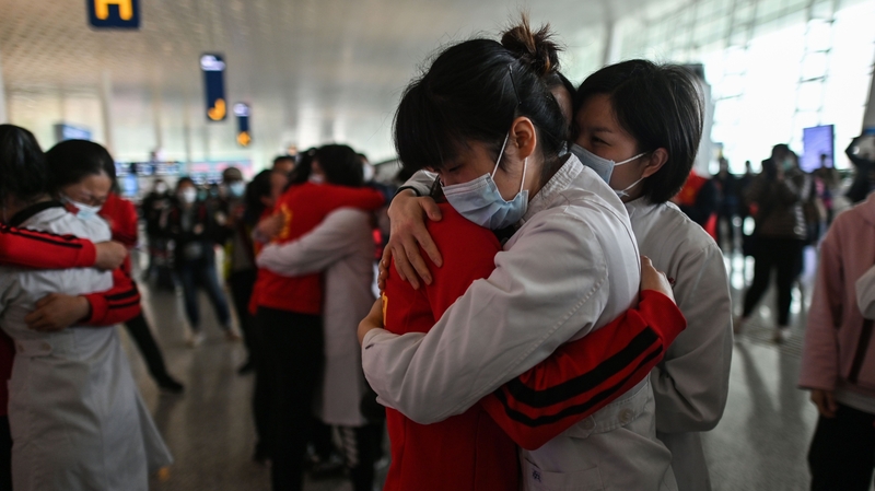 Medical staff from Jilin Province (in red) hug nurses from Wuhan after working together during the coronavirus