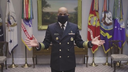 In the video Dr Jerome Adams rolls up a T-shirt and uses two rubber bands to hold it behind his ears