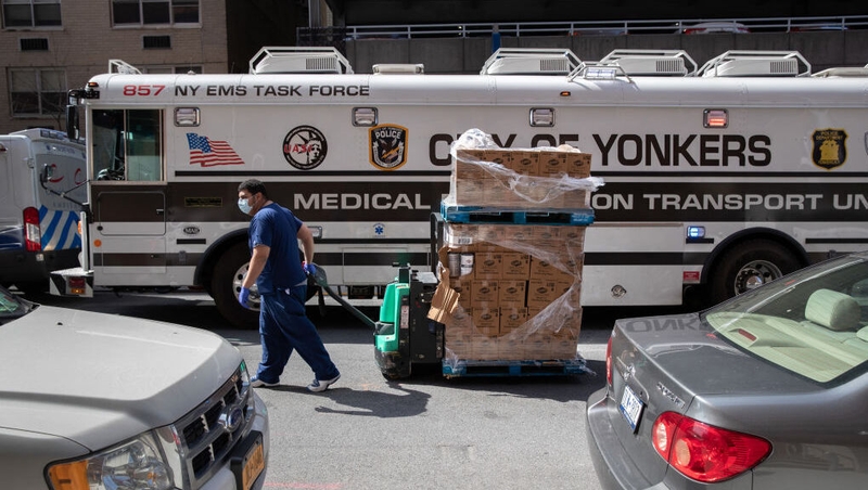 A worker pulls a pallet of disinfectant wipes past a specialised medical bus in the Bronx borough of New York