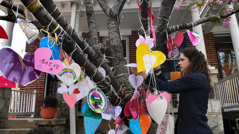 A teacher from the McKean children's school adds a heart to a tree in front of the family's home