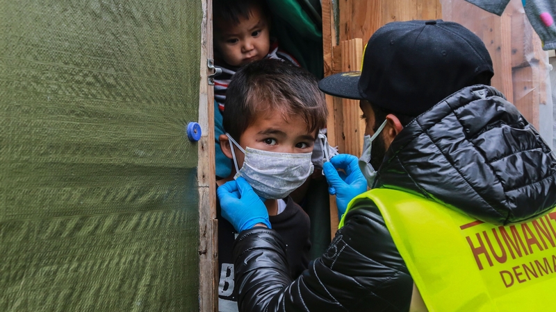 A member of the 'Team Humanity' NGO fits a mask on a child within the Moria camp