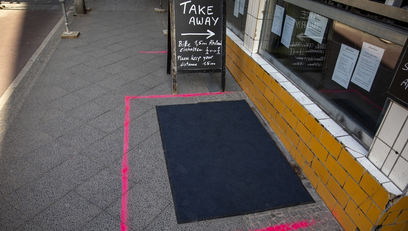 Lines direct customers where to pick up orders to keep the required distance between customers in front of a restaurant in Berlin