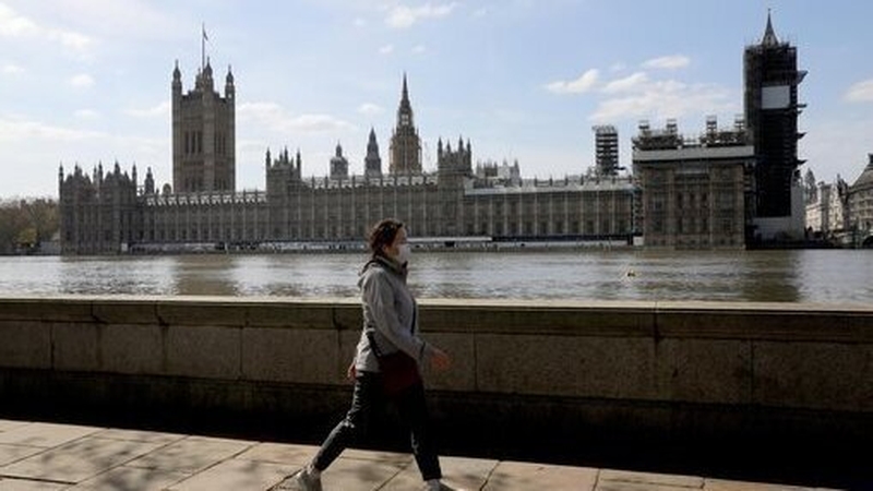 A woman wears a mask in London with Westminster in the background
