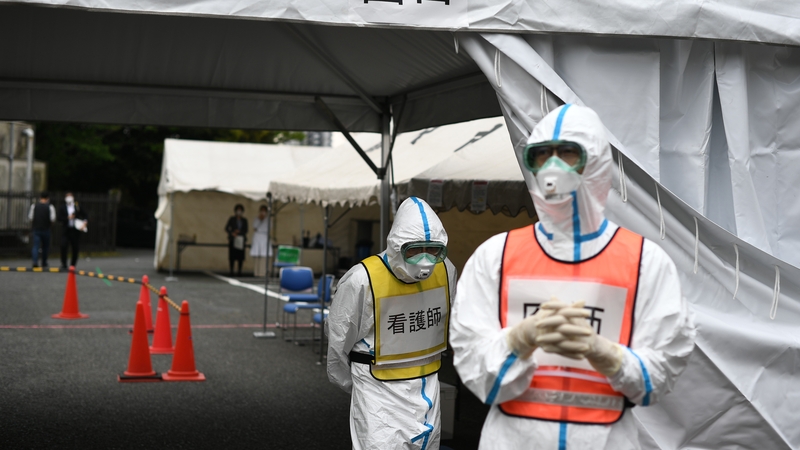 A doctor (R-in orange vest) and a nurse (C-in yellow vest) wearing protective gear in Fujisawa Prefecture, Japan