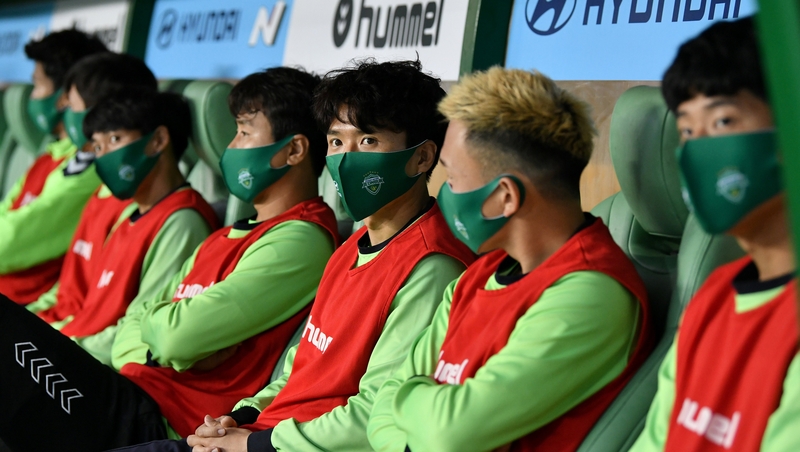 Jeonbuk Hyundai Motors players sit on the bench wearing masks