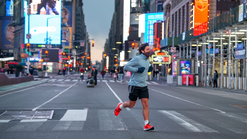 A man wearing a mask runs in an empty Times Square, New York, during the coronavirus pandemic
