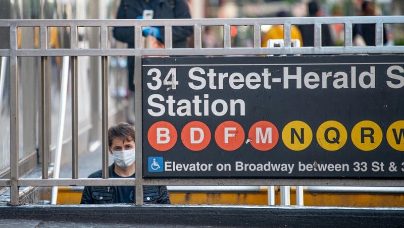 A passenger wears a facemask on his way into a subway station in New York city