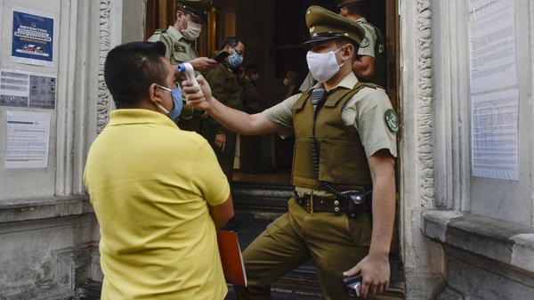 A police officer takes the temperature of a citizen at a police station in Santiago, Chile