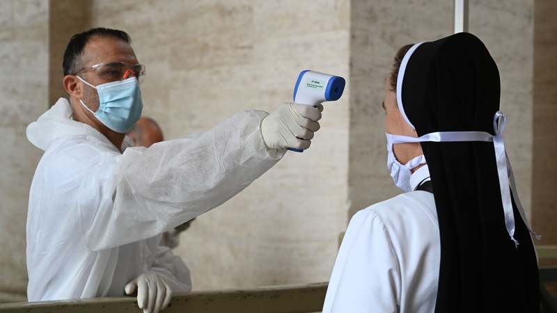A nun has her temperature checked while going through security to access St Peter's Square