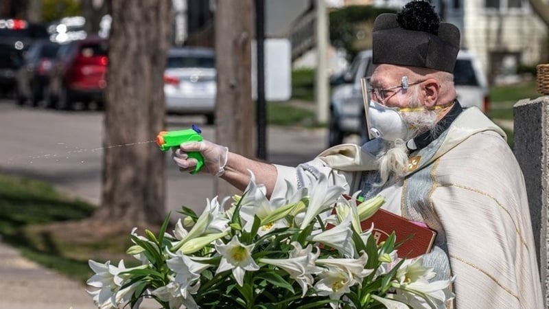 Fr Tim Pelc shoots holy water into a car window (Pics: St Ambrose Parish/Facebook)